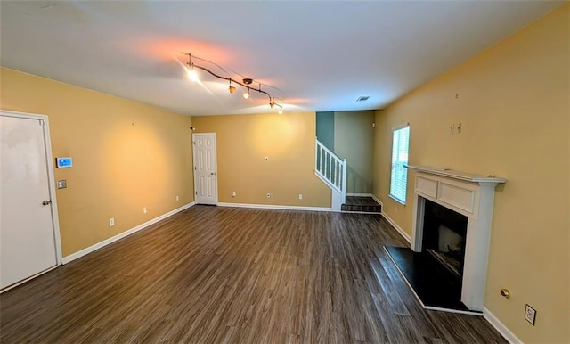 unfurnished living room with rail lighting and dark hardwood / wood-style floors