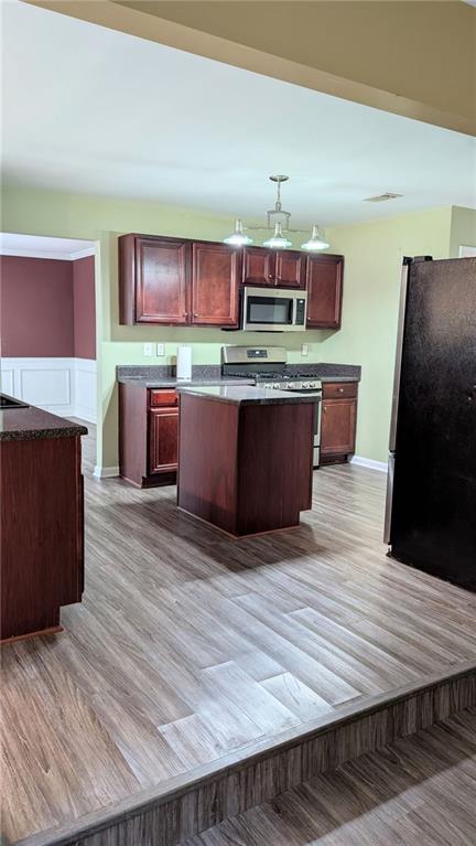 kitchen featuring a notable chandelier, a kitchen island, appliances with stainless steel finishes, and light hardwood / wood-style flooring