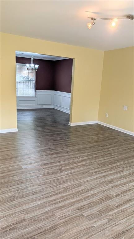 spare room with a notable chandelier and hardwood / wood-style flooring