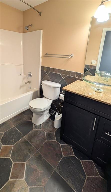 full bathroom with vanity, shower / tub combination, toilet, and tile walls