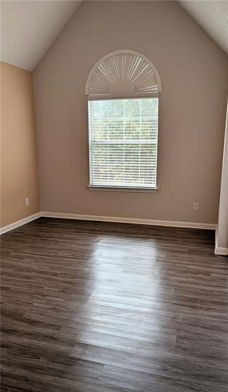 empty room with dark wood-type flooring and lofted ceiling