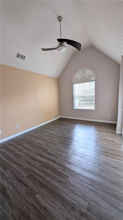 empty room with vaulted ceiling, ceiling fan, a textured ceiling, and dark hardwood / wood-style flooring