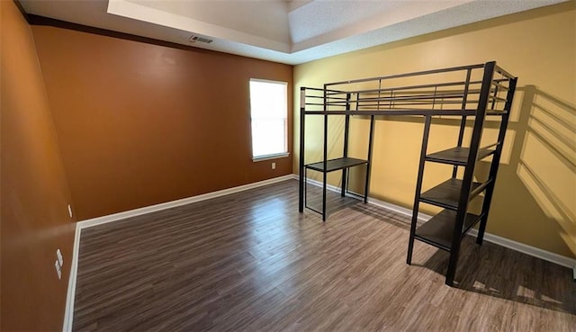 unfurnished bedroom featuring hardwood / wood-style floors and a tray ceiling