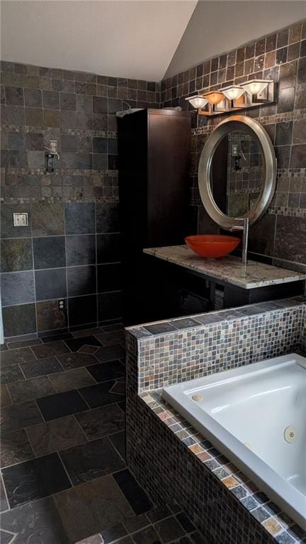 bathroom featuring tile walls, sink, vaulted ceiling, and a relaxing tiled tub