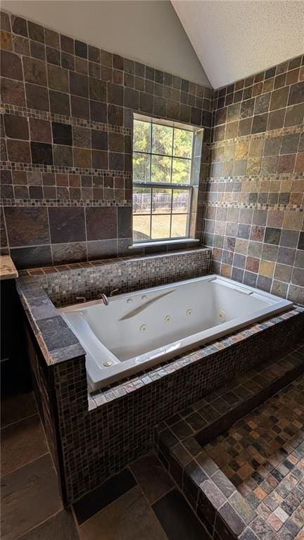 bathroom featuring tile walls, vaulted ceiling, a relaxing tiled tub, and tile patterned flooring