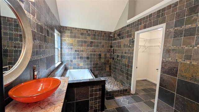 bathroom featuring tile walls, sink, vaulted ceiling, and plus walk in shower