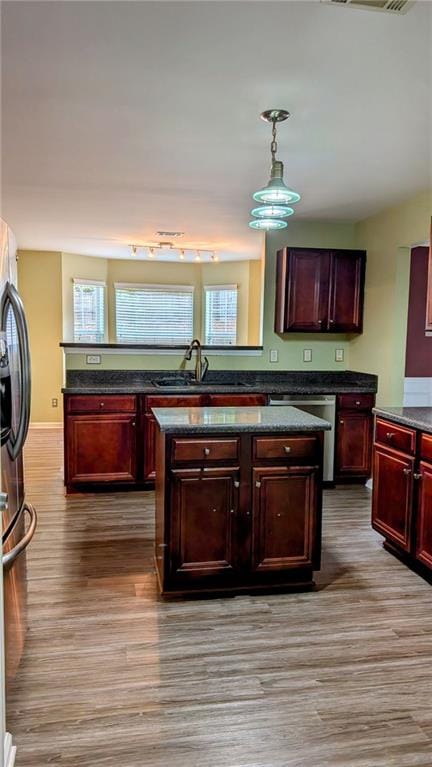 kitchen with appliances with stainless steel finishes, sink, light wood-type flooring, and hanging light fixtures