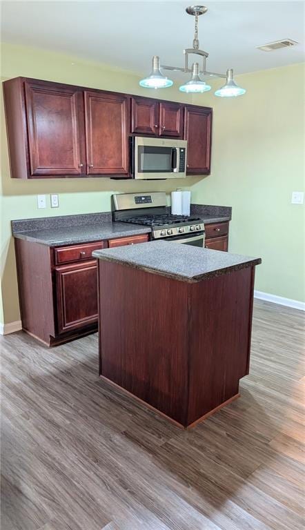 kitchen featuring stainless steel appliances, dark hardwood / wood-style flooring, a kitchen island, and hanging light fixtures