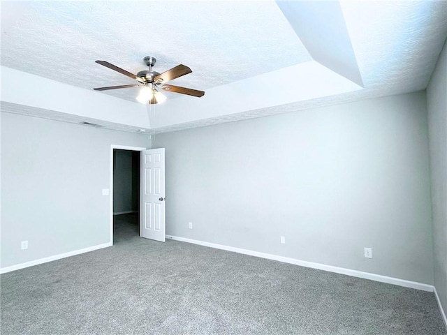 spare room with ceiling fan, a tray ceiling, a textured ceiling, and carpet flooring