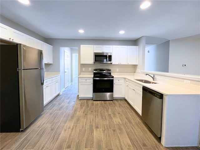 kitchen with sink, stainless steel appliances, white cabinets, and light wood-type flooring