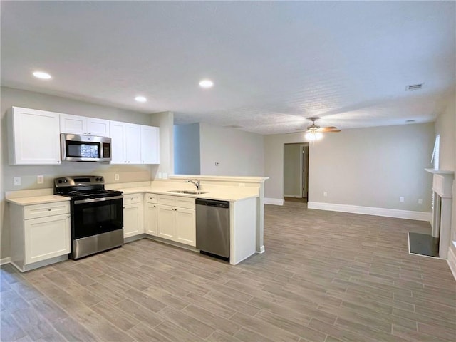 kitchen with white cabinetry, sink, light hardwood / wood-style floors, kitchen peninsula, and stainless steel appliances