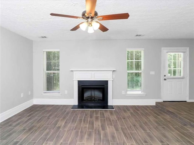 unfurnished living room featuring ceiling fan, dark wood-type flooring, and a textured ceiling