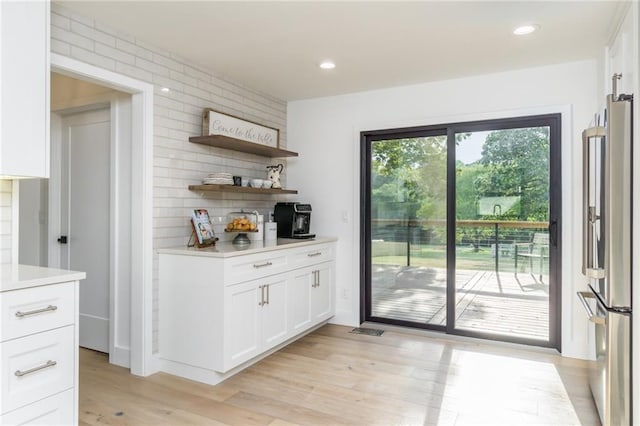 kitchen with tasteful backsplash, light wood-style floors, light countertops, and freestanding refrigerator