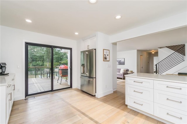 kitchen with recessed lighting, light countertops, white cabinets, light wood-style floors, and high quality fridge