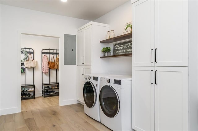 laundry area with light wood-type flooring, electric panel, washing machine and dryer, cabinet space, and baseboards