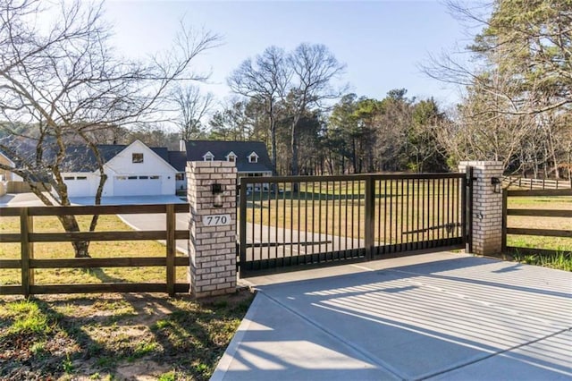 view of gate with fence and a lawn