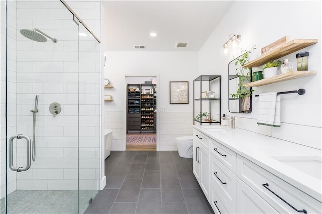 full bathroom featuring visible vents, double vanity, a stall shower, tile patterned floors, and tile walls