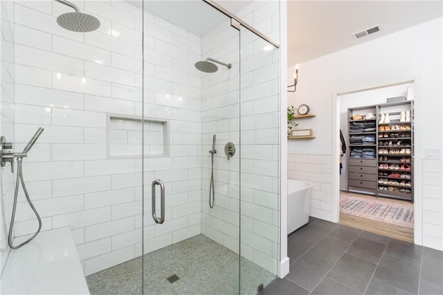 full bath with visible vents, a freestanding bath, a shower stall, tile walls, and tile patterned floors