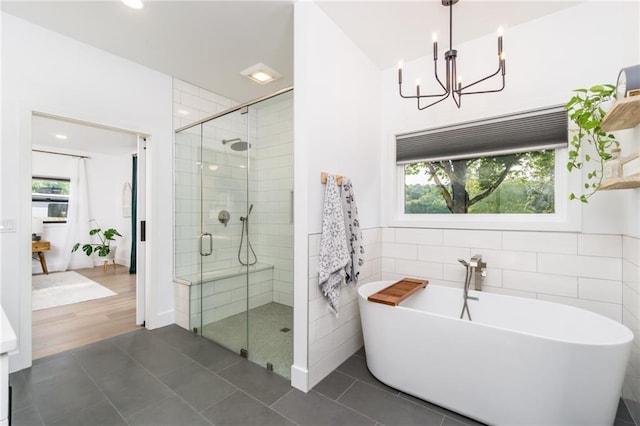 bathroom featuring tile patterned flooring, a shower stall, tile walls, and an inviting chandelier