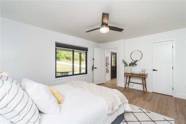 bedroom featuring a ceiling fan, baseboards, and light wood finished floors