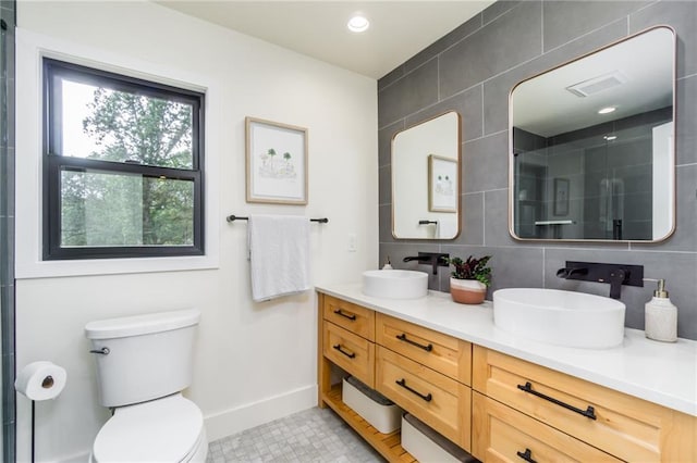 full bath with a sink, baseboards, a shower with shower door, and double vanity