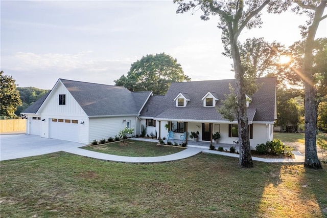 view of front facade with a front lawn, roof with shingles, covered porch, a garage, and driveway