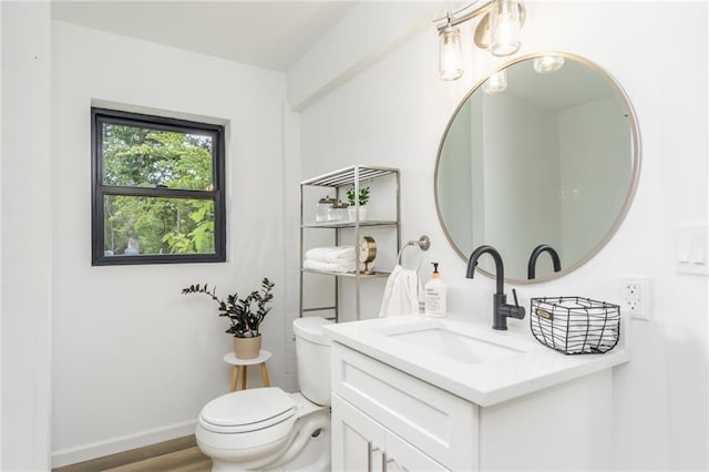 bathroom with toilet, vanity, baseboards, and wood finished floors