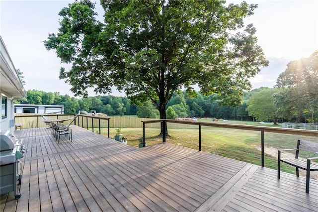 wooden terrace with outdoor dining area, a yard, and fence