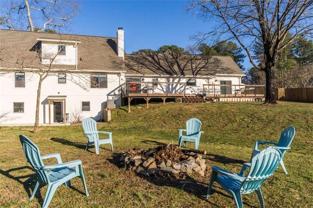 back of house with fence, a wooden deck, an outdoor fire pit, a chimney, and a yard