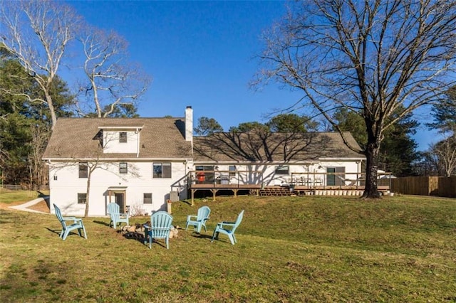 back of property featuring a lawn, a chimney, a deck, and fence