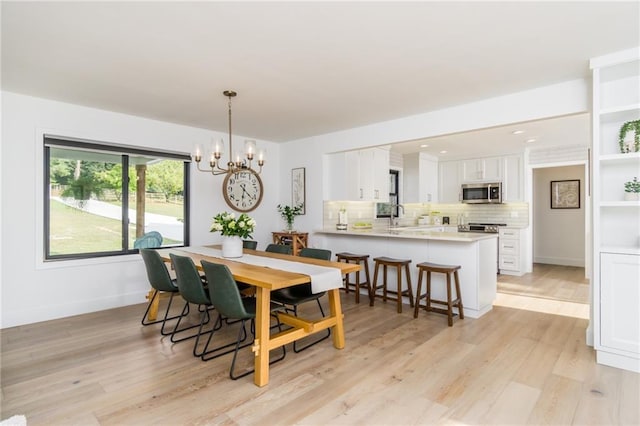 dining area featuring light wood-style flooring, baseboards, and a chandelier