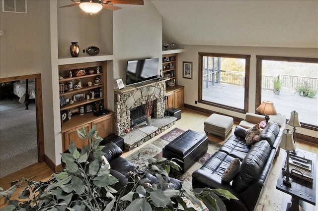 living room featuring vaulted ceiling, built in features, a fireplace, and light hardwood / wood-style flooring