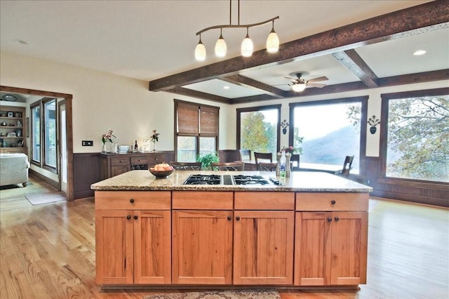 kitchen featuring light stone counters, light wood-type flooring, gas cooktop, pendant lighting, and beam ceiling