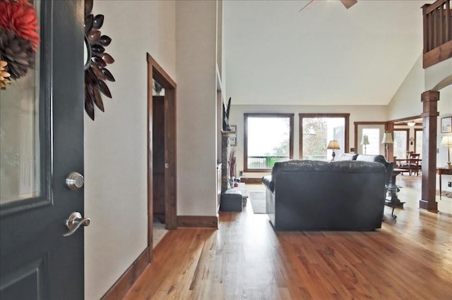 living room featuring ceiling fan, high vaulted ceiling, light hardwood / wood-style flooring, and ornate columns