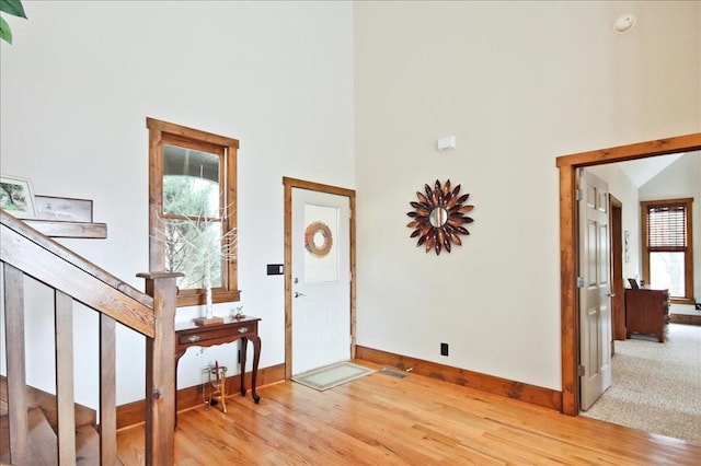 foyer featuring a towering ceiling and light hardwood / wood-style flooring