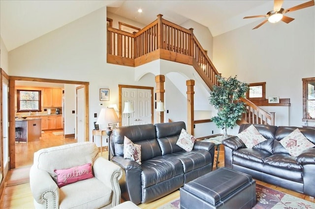 living room featuring ceiling fan, high vaulted ceiling, and light wood-type flooring