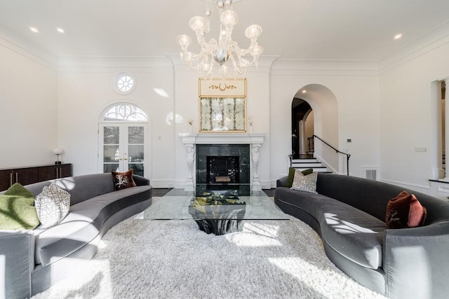 living area with ornamental molding, arched walkways, an inviting chandelier, and a premium fireplace