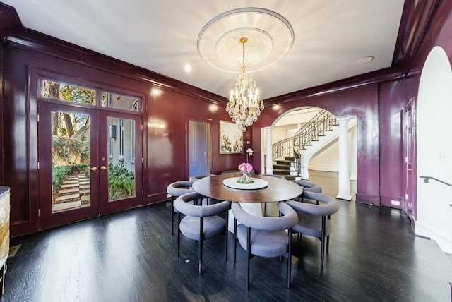 dining room with dark wood-style floors, arched walkways, french doors, ornamental molding, and stairs