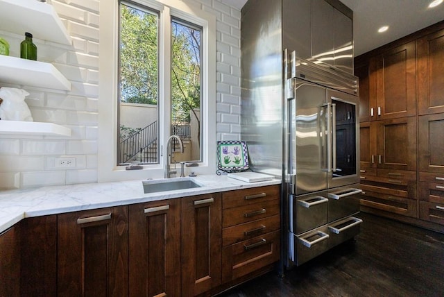 kitchen with light stone counters, recessed lighting, dark wood-type flooring, and a sink