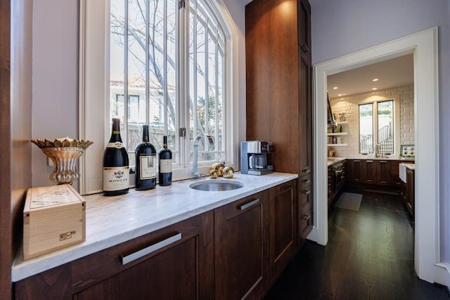 bar with dark wood-type flooring, a healthy amount of sunlight, a sink, and decorative backsplash