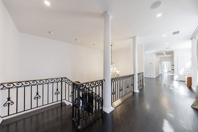 hall with decorative columns, visible vents, wood finished floors, a notable chandelier, and recessed lighting