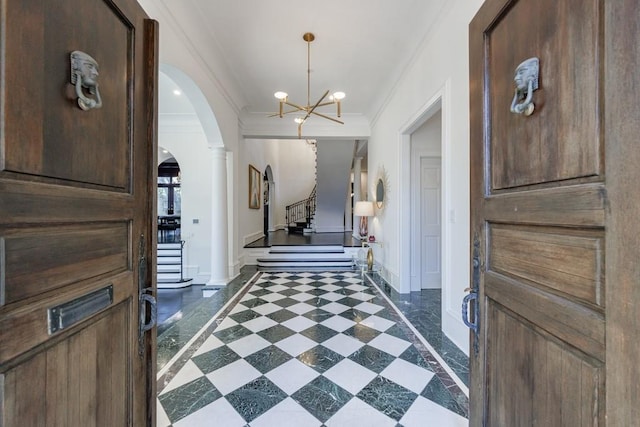 foyer featuring arched walkways, baseboards, stairway, decorative columns, and crown molding