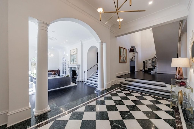 interior space with arched walkways, baseboards, ornamental molding, stairway, and decorative columns