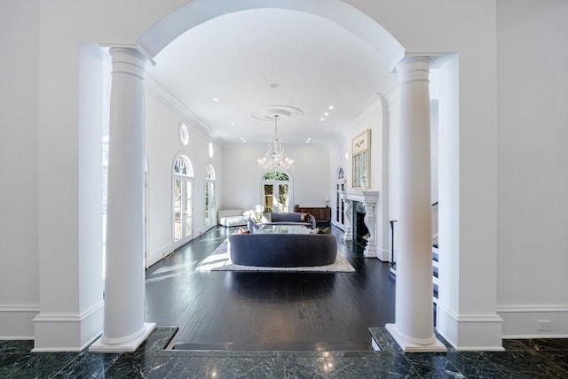 entryway featuring crown molding, baseboards, a fireplace, and ornate columns