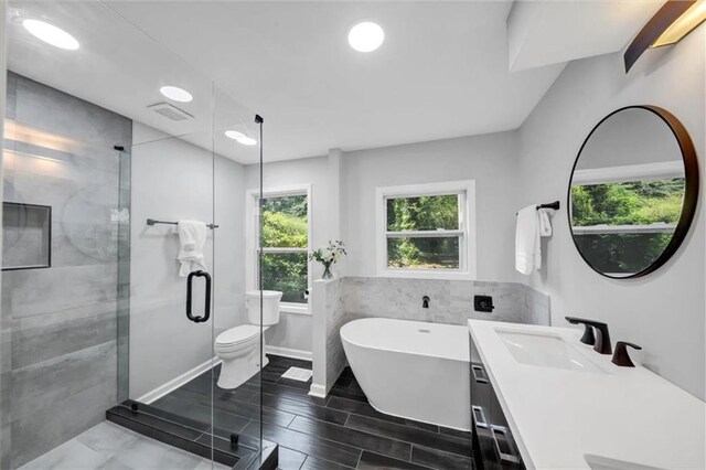 full bathroom featuring vanity, plus walk in shower, tile walls, and toilet