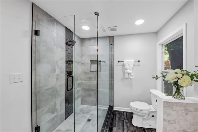 bathroom featuring wood-type flooring, toilet, and a shower with door