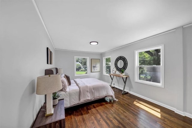 bedroom featuring dark hardwood / wood-style floors, multiple windows, and crown molding