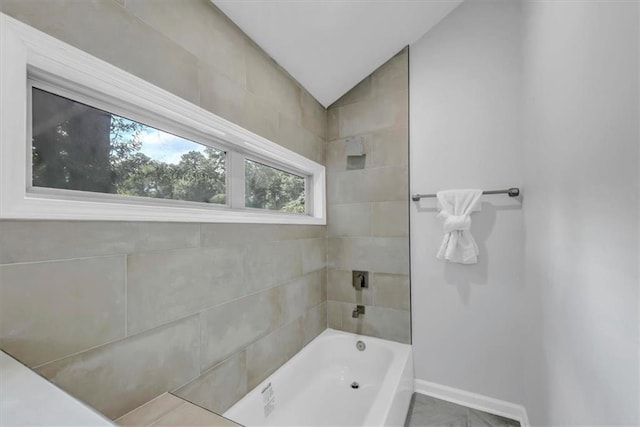 bathroom with lofted ceiling and tiled shower / bath