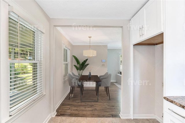 hall featuring crown molding, baseboards, light wood-style flooring, and a notable chandelier