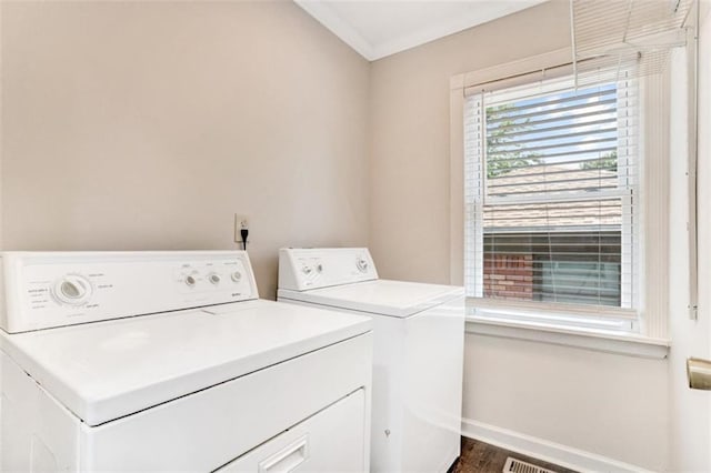 clothes washing area featuring laundry area, baseboards, washing machine and dryer, and dark wood finished floors